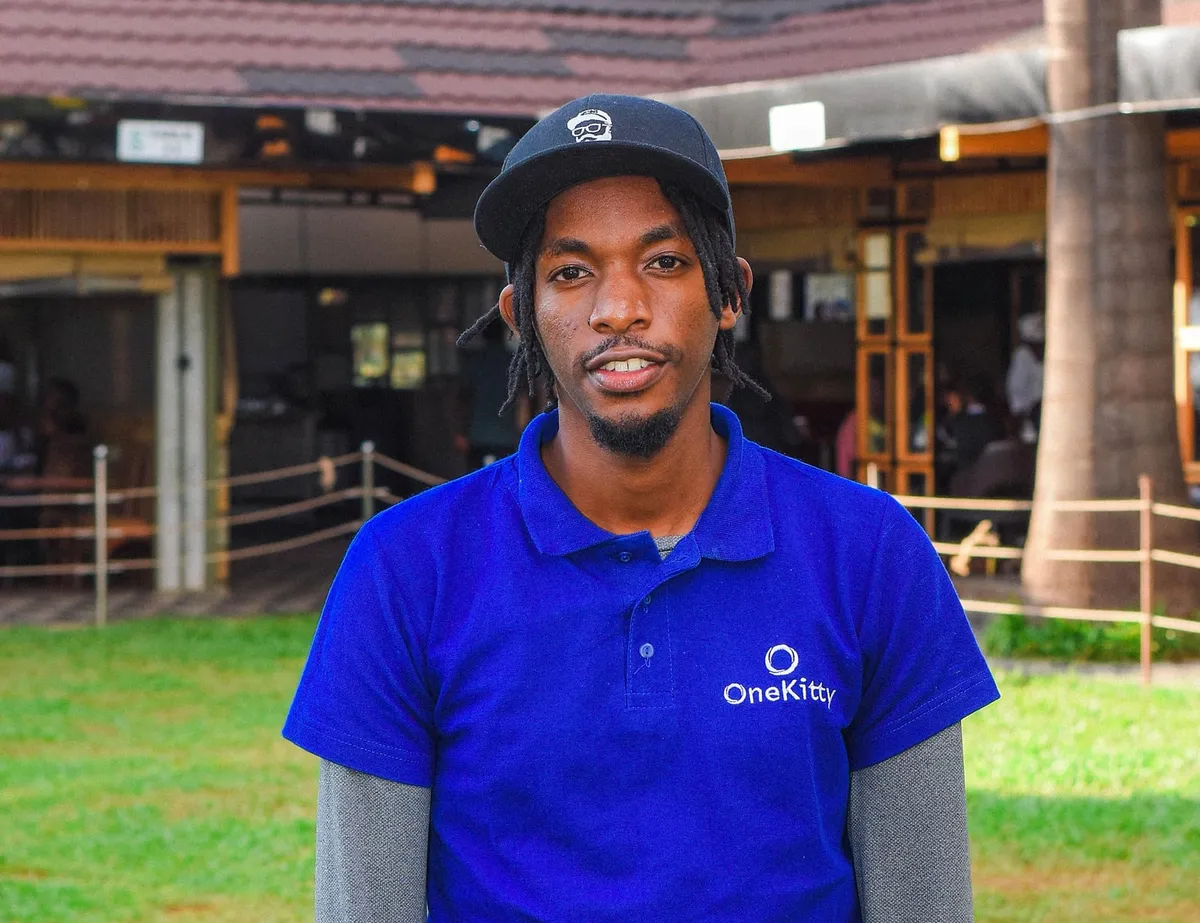 Evanrobby Macharia outdoors in Nairobi, wearing a cap and a blue OneKitty polo